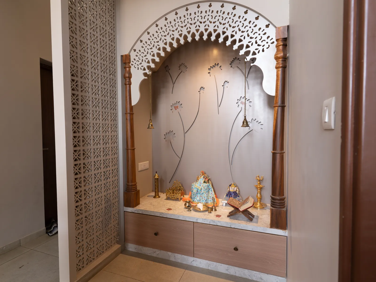 Pooja unit with carved white arch and jaali screen — Amlan's Residence